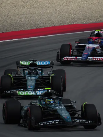 Two Aston Martin Formula 1 cars leading a Racing Bulls car through a corner during the 2024 Spanish Grand Prix.