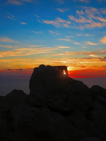 A stone watchtower silhouetted against a fading sunset above the sea at Dingli Cliffs