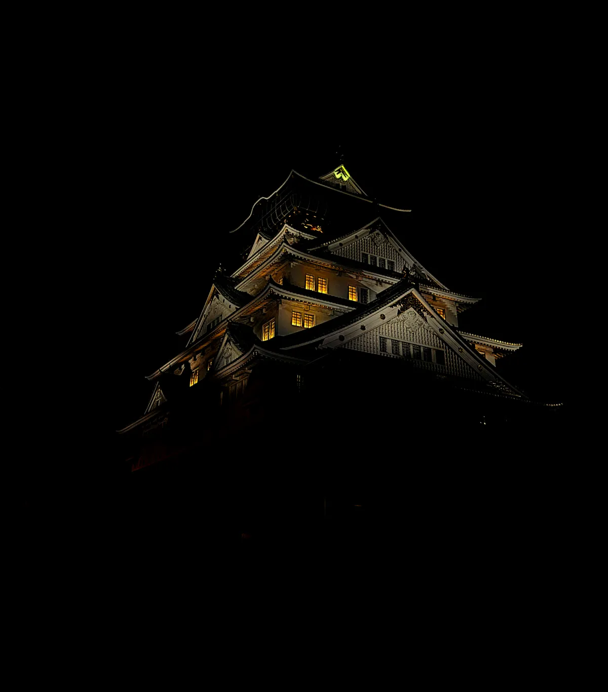 Osaka Castle's tiered rooftops glowing gold against the night sky.