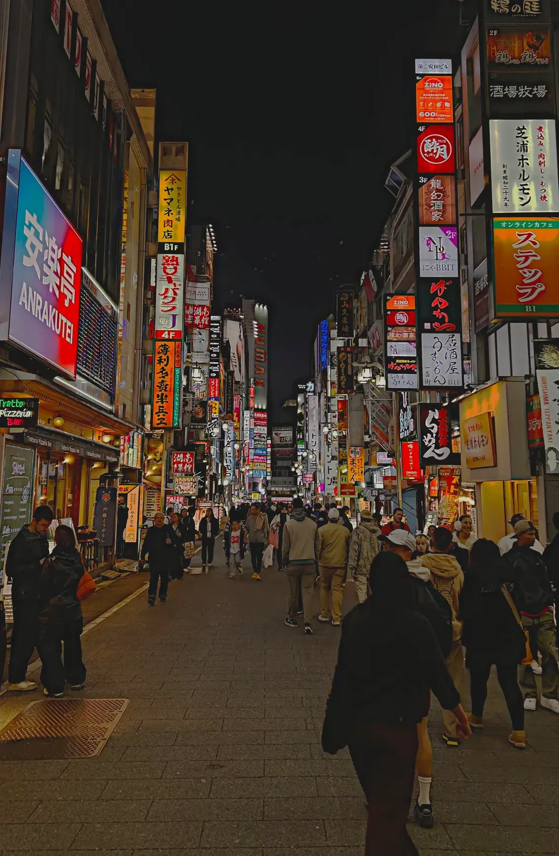 A crowded Tokyo side street glowing with neon signs and restaurant lanterns at night in the Shibuya district.