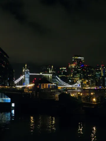 Tower Bridge illuminated against the London skyline, reflected in the Thames.